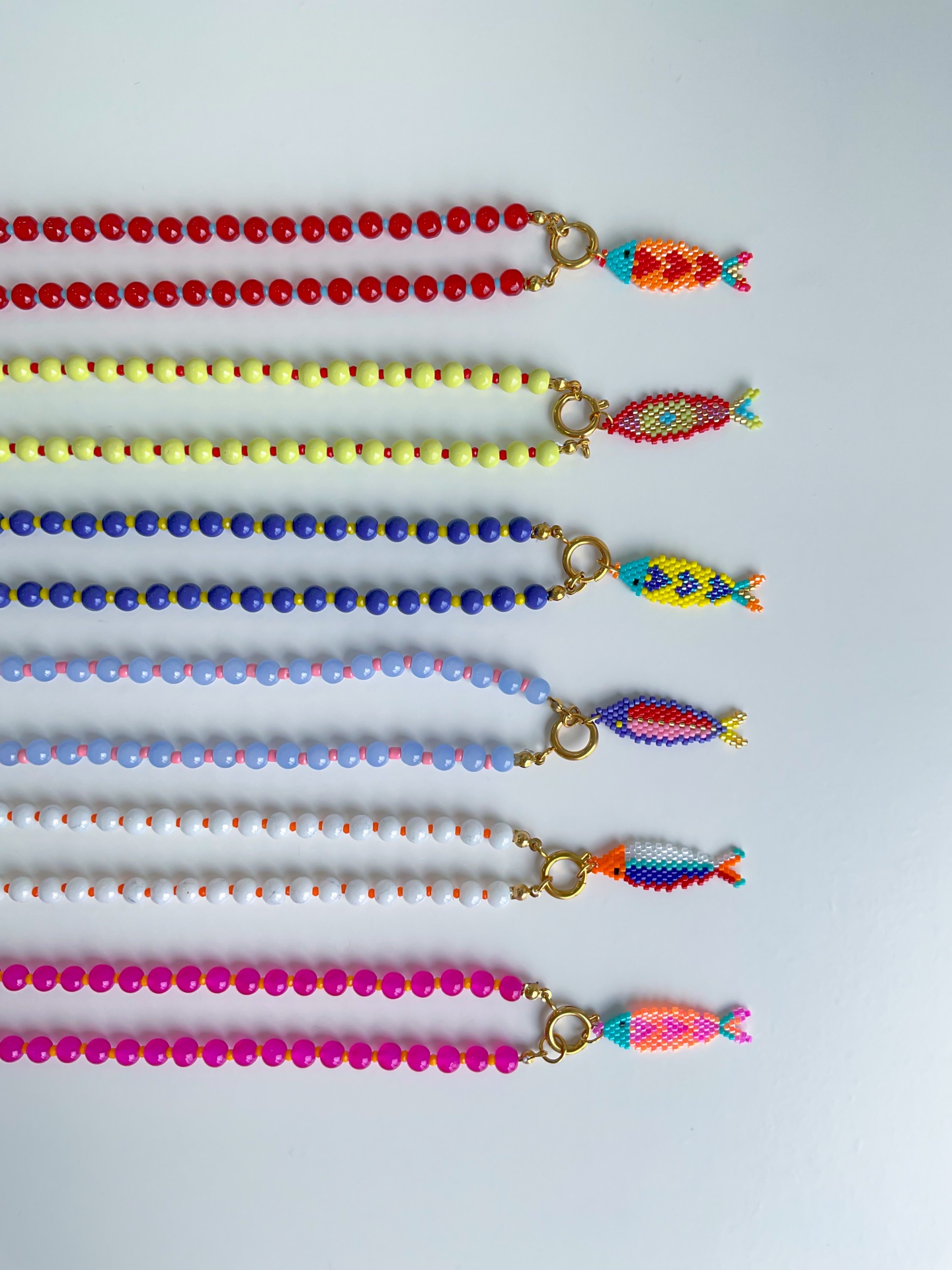 Colares SARDINHAS Seis colares coloridos com pendentes em forma de peixe feitos de contas sobre fundo branco