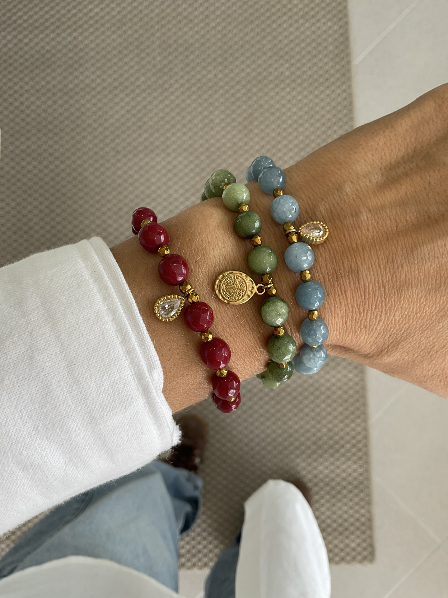 Pulseiras Pedras naturais Pulseiras de pedras vermelhas, verdes e azuis com pendentes dourados no pulso