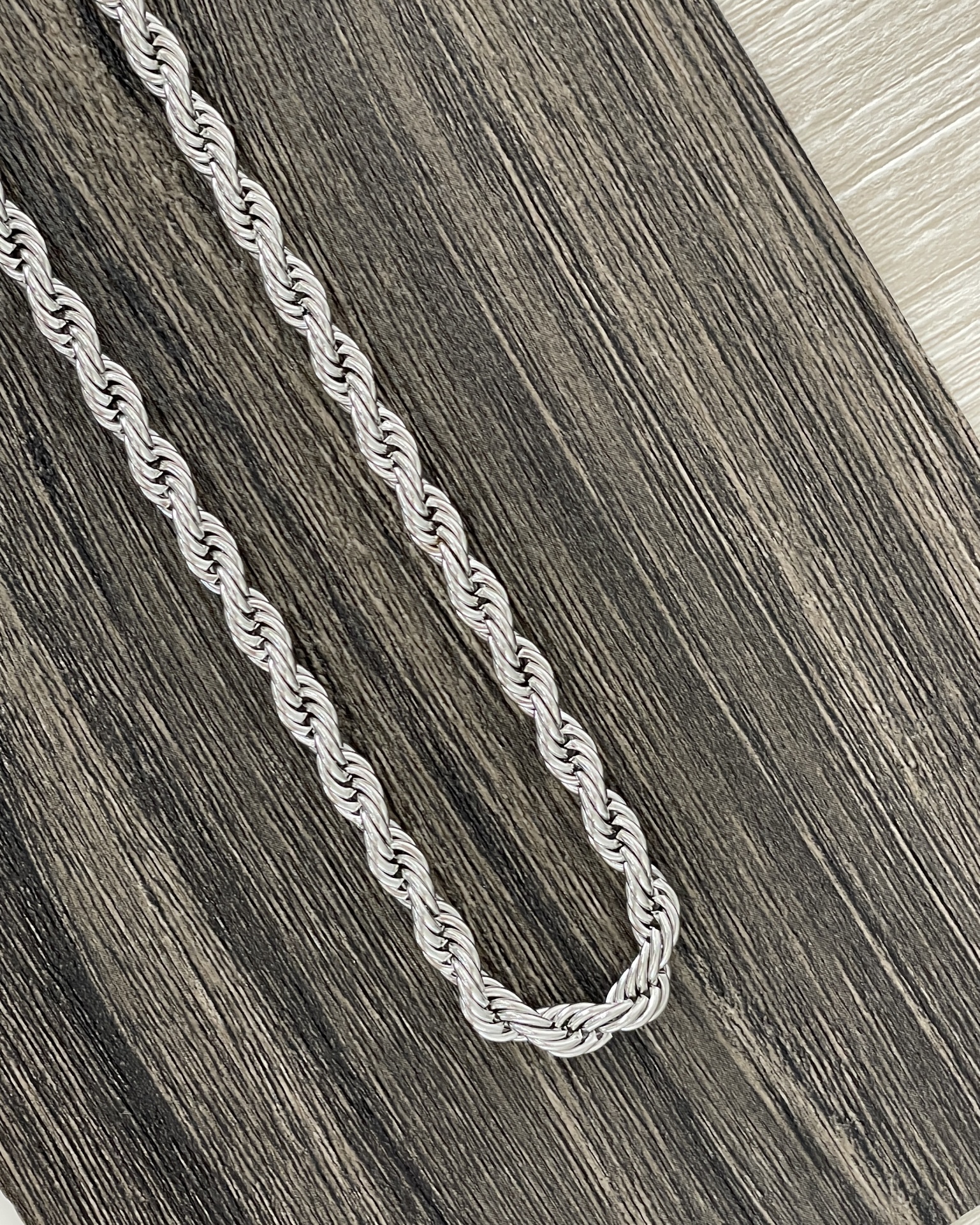 COLARES HOMEM Colar de corrente torcida prateada sobre madeira escura