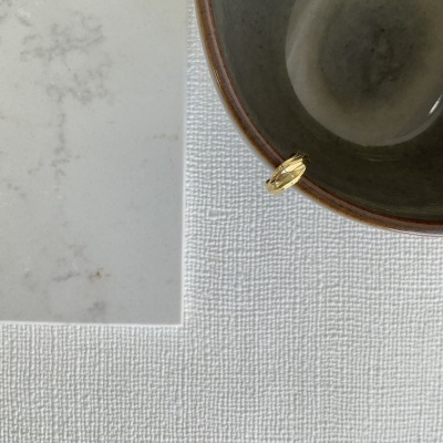 Copo de vidro cinzento com rebordo castanho sobre superfície branca texturada