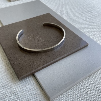 Bracelete prateado sobre placas de diferentes cinzentos em superfície têxtil clara