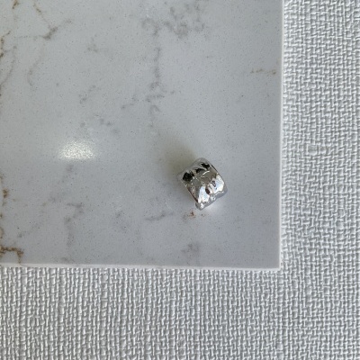 Anel de prata texturizado sobre superfície branca marmorizada