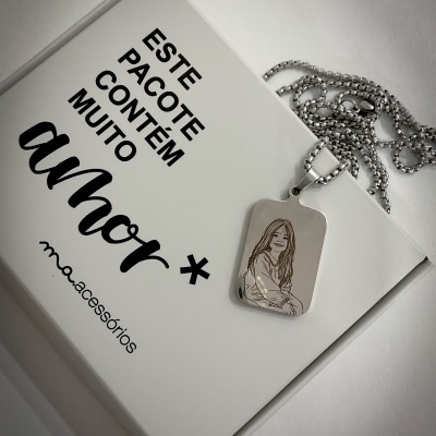 Colar em aço inoxidável com pingente retangular gravado com desenho de rapariga sobre caixa branca com texto