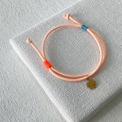 Pulseira cor-de-rosa com pendente metálico dourado em forma de folha