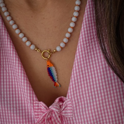Colar de contas branca com pendente colorido em forma de peixe e blusa rosa xadrez
