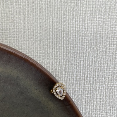 Anel dourado com pedras sobre prato cinza e fundo branco texturizado