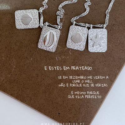 Colares prateados com pendentes de conchas e estrela do mar sobre superfície castanha com texto em português