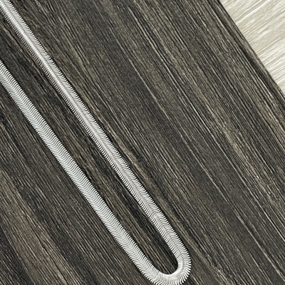 Corrente de prata com padrão texturizado sobre madeira escura