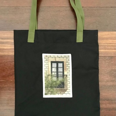 Saco de tecido preto com alças verdes e imagem de janela com varanda