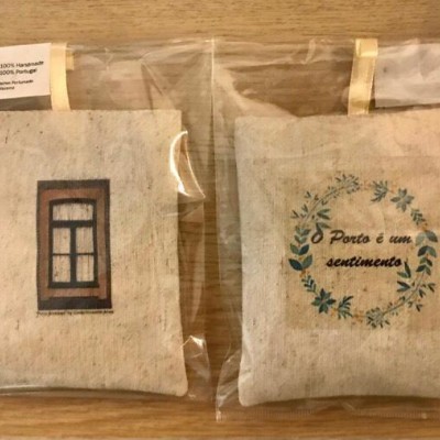 Duas almofadas pequenas bege com uma janela e frase sobre Porto em embalagem plástica