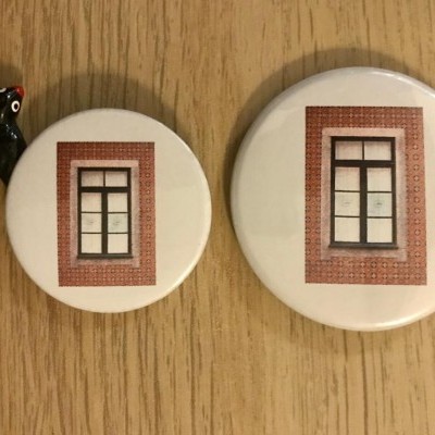Dois ímanes redondos com imagens de janelas em superfície de madeira