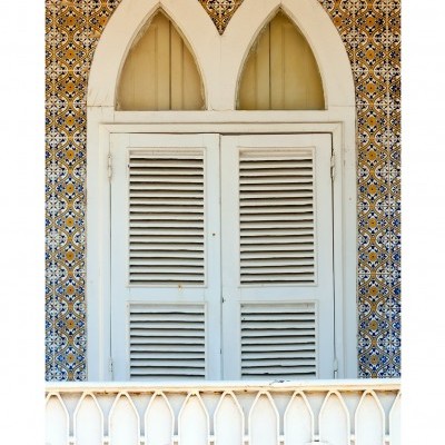 Janela branca com persianas de madeira e azulejos coloridos ao redor