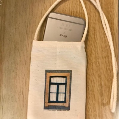 Mala de tecido bege com imagem de janela azul e iPhone prateado