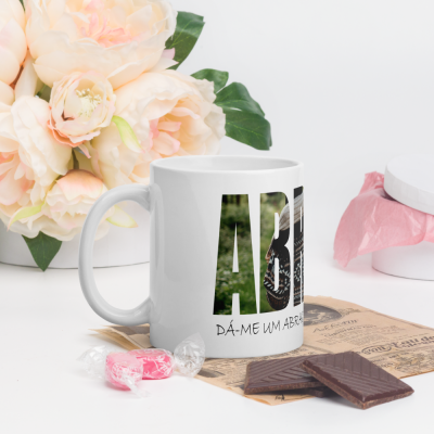 Caneca branca com texto parcial, doces rosa, barras de chocolate e flores brancas e rosa