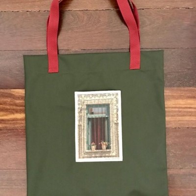 Saco verde-escuro com alças vermelhas e imagem de janela com plantas