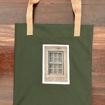 Saco de tecido verde com alças bege e imagem de janela