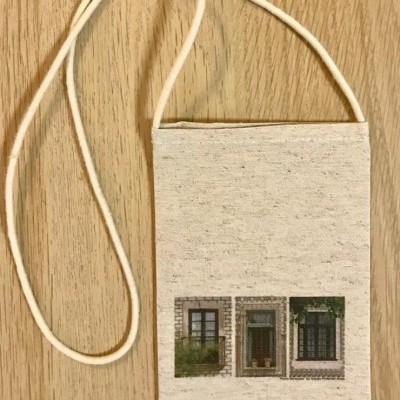 Carteira de tecido bege com imagem de três janelas em pedra