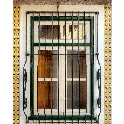 Janela portuguesa com grade de ferro e azulejos amarelos ao redor