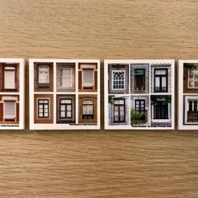 Quatro conjuntos de azulejos decorativos com imagens de fachadas e janelas de edifícios colocados sobre mesa de madeira