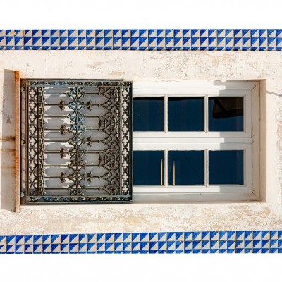 janela branca com grades de ferro e moldura de azulejos azuis e brancos