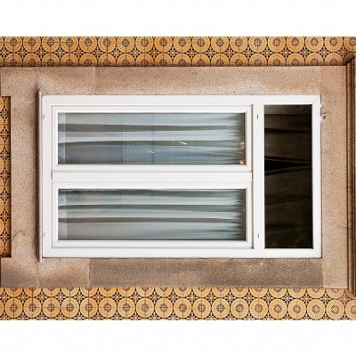 Janela branca com moldura de granito e azulejos decorativos.