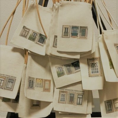 Sacos de tecido bege com estampas de janelas e texto pendurados