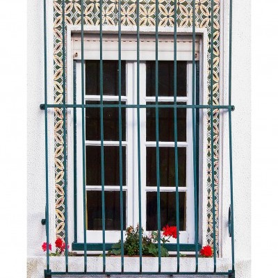 Janela tradicional com grade de proteção e azulejos decorativos