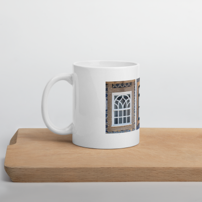 Caneca branca com imagem de janela em parede castanha com ladrilhos azuis