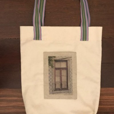 Saco de tecido branco com alças às riscas e imagem de janela antiga impressa