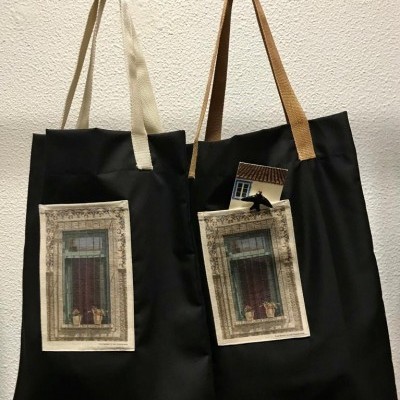 Dois sacos de tecido preto com bolsos estampados de janelas antigas pendurados