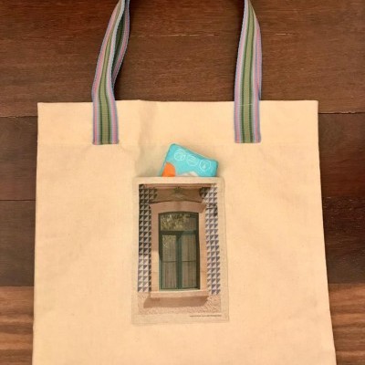 Saco bege com alças coloridas e imagem de janela frontal