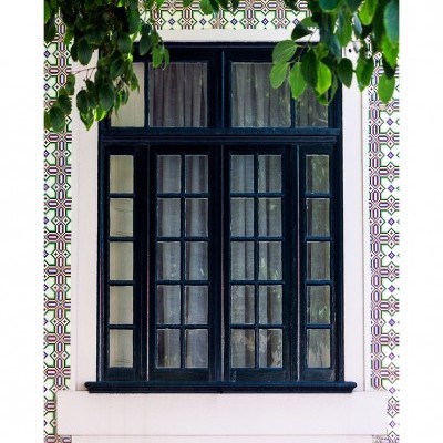 Janela preta com vidros e azulejos decorativos.