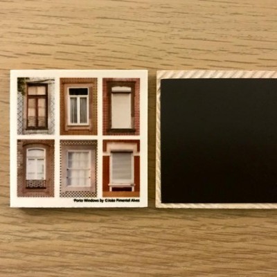 Duas placas quadradas, uma com fotos de janelas e outra preta lisa, sobre madeira clara.