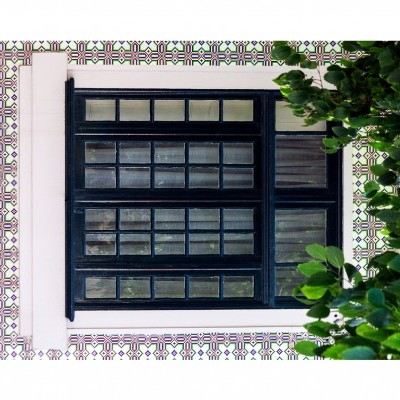 Janela preta de madeira com painéis de vidro e azulejos coloridos na parede ao redor