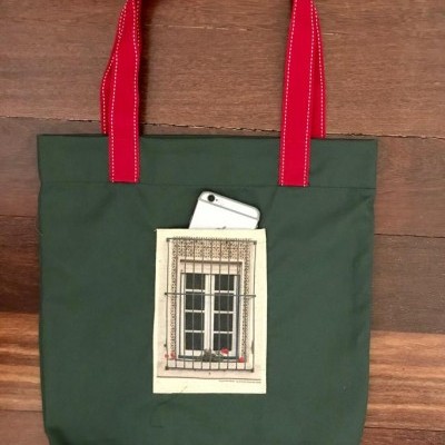 Saco verde com alças vermelhas e bolso branco com imagem de janela