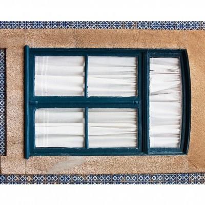 Janela azul escura com cortinas brancas em parede revestida com azulejos azuis e brancos