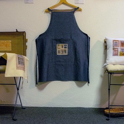 Avental azul com padrão quadrado pendurado entre duas cadeiras com almofada e tecido estampados