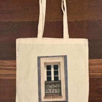 Saco de pano bege com imagem de janela com azulejos azuis e grelha metálica