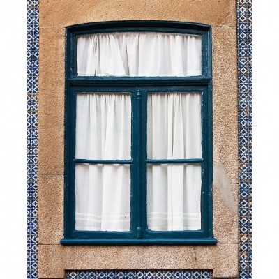 Janela azul com cortinas brancas e azulejos portugueses