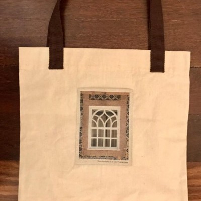 Saco de tecido bege com alças castanhas e imagem de janela