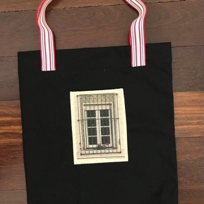 Saco preto com alças listradas e imagem de janela central