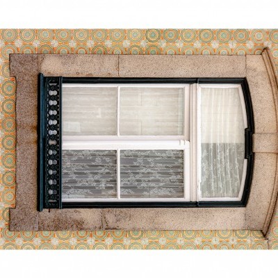 Janela de vidro com moldura de metal preta numa parede revestida com azulejos decorativos