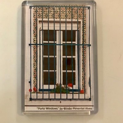 Imã com imagem de janela típica com grades azuis e moldura decorada.