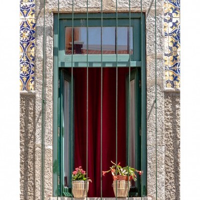 Janela verde com grelha, vasos de plantas e azulejos tradicionais azuis e amarelos