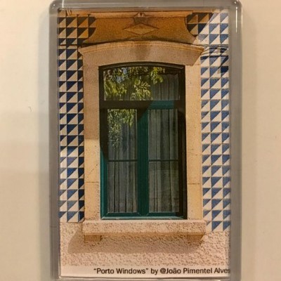 Janela verde com cortinas e azulejos azuis e brancos ao redor numa moldura transparente