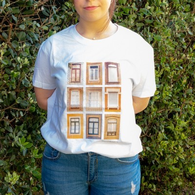 Pessoa com t-shirt branca estampada e calças de ganga à frente de folhagem verde