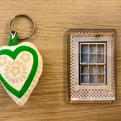 Chaveiro de tecido em forma de coração verde e bege ao lado de íman com imagem de janela