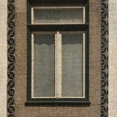 Janela branca de madeira com moldura de azulejos azuis e parede bege