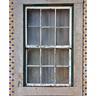 Janela de madeira com pintura branca descascada numa parede com azulejos geométricos