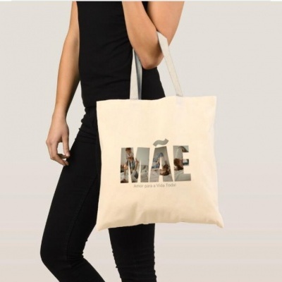 Tote bag bege com texto MÃE e frase Amor para a Vida Toda, sendo usada por mulher